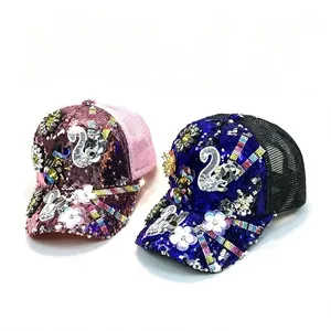 Detalle de gorras de lentejuelas con diseño de cisne de strass y parches florales
