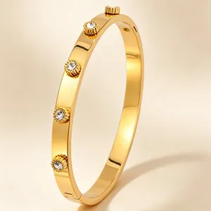 Gros plan d'un bracelet jonc en acier titane doré avec cinq cristaux ronds incrustés.