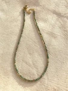 Detailed macro view of a slender natural stone beaded necklace on textured linen fabric