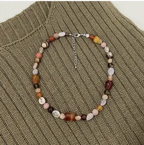 Close-up of vintage multi-color irregular natural stone necklace on textured knit fabric