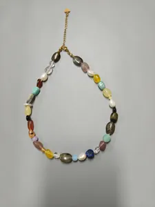 Detailed view of an irregular colorful natural stone necklace featuring a gold heart tag