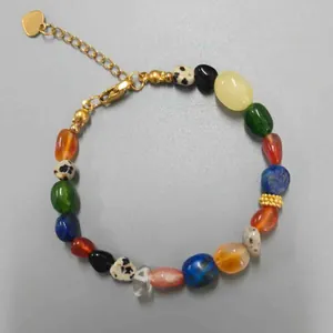Macro view of multicolored irregular natural stone beads on a gold-tone bracelet chain