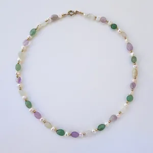 Detailed view of irregular colored natural stones and pearls on a vintage necklace.