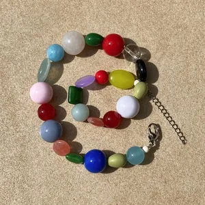 Close-up detail of a vintage necklace featuring irregular colorful stone beads and a silver clasp.