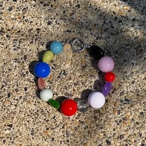 Colorful irregular natural stone necklace with metal toggle clasp on textured ground