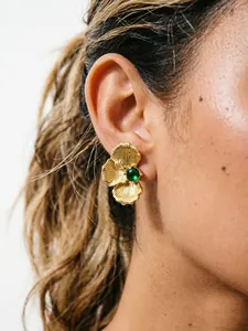 Detail shot of vintage gold flower petal stud earrings with green stone on model
