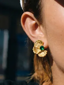 Close-up of vintage gold-plated stainless steel flower stud earring with green crystal