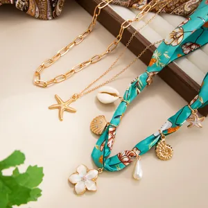 Makrodetail einer Halskette im Meeres-Stil mit Seidenband, Seestern- und Muschelanhängern.