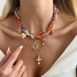 Detailaufnahme einer mehrlagigen Goldhalskette mit Sonnen- und Kreuzanhängern.