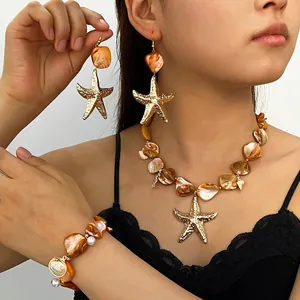 Modella indossa set di gioielli con stelle marine dorate e conchiglie per la spiaggia