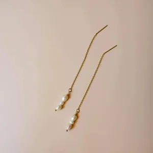 Close-up of elegant long threader earrings with natural white freshwater pearls