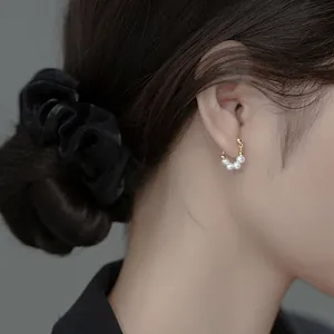 Close-up detail of elegant vintage gold hoop earrings with white freshwater pearls on a model.