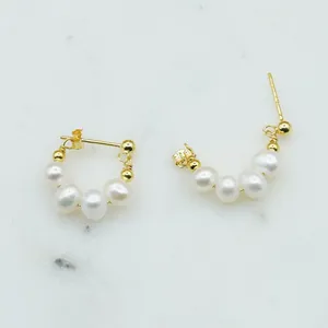 Close-up detail of elegant vintage gold hoop earrings with white freshwater pearls