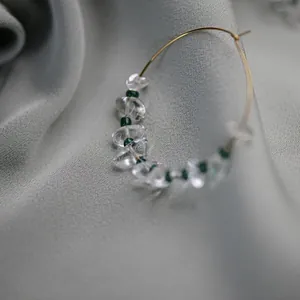 Macro view of a vintage gold hoop earring with clear stones and green beads