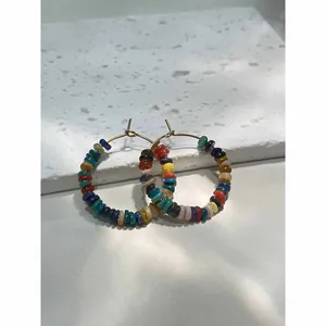 Detailed view of colorful beaded hoop earrings on a clean white textured background.