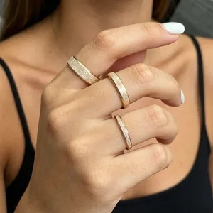 Detail view of three frosted rose gold plain band rings with varying widths on fingers