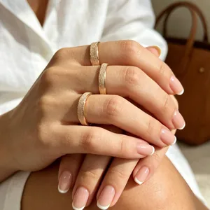 Detailed close-up of three elegant frosted gold minimalist band rings on fingers