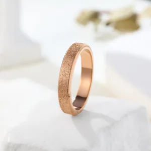 Detailed macro view of a rose gold frosted texture minimalist band ring on a white stone