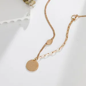 Close-up detail of rose gold double-layered necklace featuring engraved round coin pendants