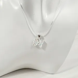 Gros plan d'un pendentif papillon iridescent sur un collier élastique transparent