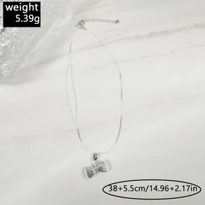 Détail macro d'un collier élastique invisible avec pendentif nœud argenté et spécifications.