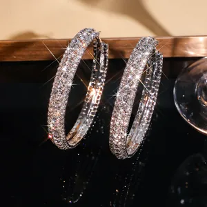 Detailopname van oversized C-vormige oorringen volledig bezet met fonkelende strass-steentjes