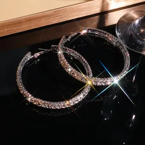 Detailopname van grote fonkelende strass oorringen met klauwkettingontwerp op zwart