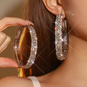Macro detail van oversized C-vormige zilveren oorringen bedekt met fonkelende strass