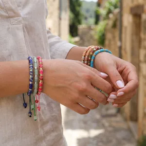 Detail shot of colorful handmade semi-precious stone barrel bead bracelets on person's wrists