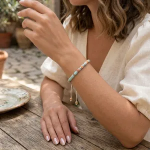 Detailed view of a handmade beaded bracelet with blue and peach stones on a model's wrist