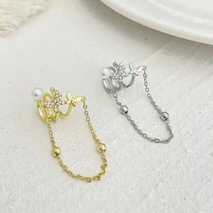 Detailed view of gold and silver butterfly ear cuffs with long chain tassels and pearls