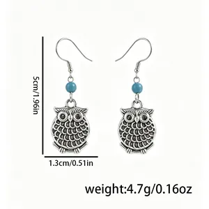 Détail de boucles d'oreilles chouette vintage argentées avec perles turquoise et mesures