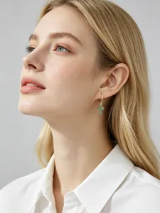 Mannequin portant des créoles croix en or avec zircons verts, style chic français.