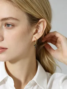 Gros plan de boucles d'oreilles créoles dorées avec pendentif croix en zircone