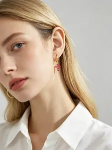 Détail d'une boucle d'oreille créole en croix dorée avec zircons roses sur un mannequin