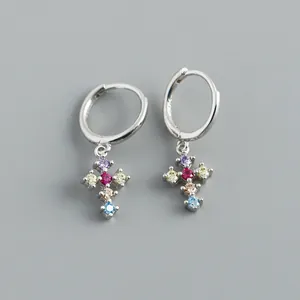 Détail de boucles d'oreilles créoles en argent 925 avec croix en zircons colorés.