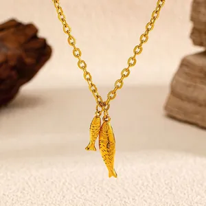 Exquisites Detail einer Halskette mit doppeltem Fisch-Anhänger in poliertem Gold-Edelstahl