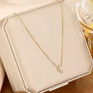Close-up of a delicate gold four-leaf clover necklace with sparkling clear crystals