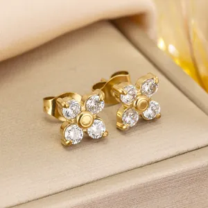 Detail view of elegant gold four-leaf flower stud earrings set with sparkling crystals