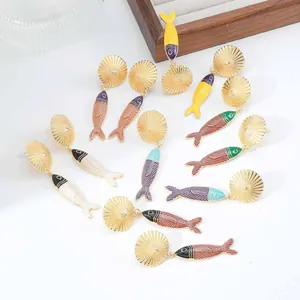 Primo piano di orecchini colorati a forma di pesce in stile bohémien per la spiaggia estiva.