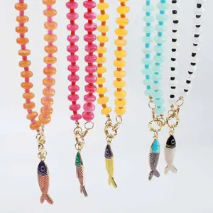 Dettaglio di orecchini boho di perline colorate con pendenti a forma di pesce smaltato