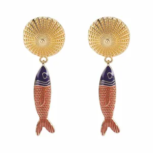 Dettaglio di orecchini a pesce in stile bohémien con top dorati e vivaci squame rosse