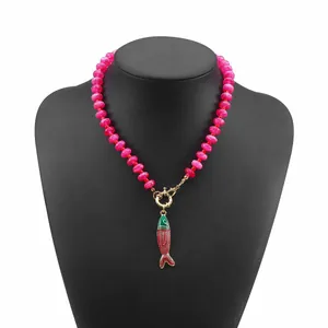 Primo piano di una collana bohémien con perline rosa e un vivace ciondolo a forma di pesce