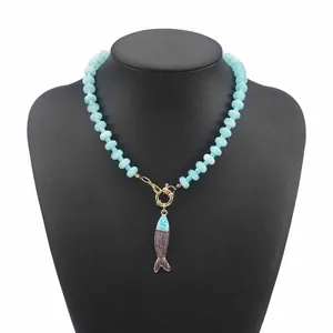 Dettaglio di una collana di perline azzurre con ciondolo a pesce su un manichino