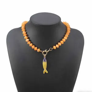 Primo piano di collana bohémien con perline arancioni e ciondolo a forma di pesce