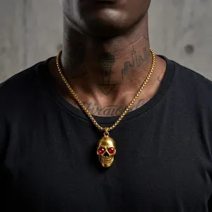 Detail view of a punk-style gold skull pendant with red eyes on a stainless steel chain.