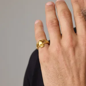 Vue détaillée d'une bague Claddagh en acier titane plaqué or 18 carats sur un doigt.