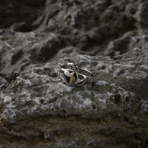 Vue détaillée d'une bague Claddagh en argent avec cœur et couronne sur une roche texturée.