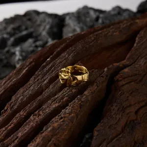 Détail d'une bague Claddagh en acier titane plaqué or 18 carats sur bois rustique.