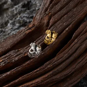 Vue macro détaillée de bagues Claddagh en or et argent sur fond de bois rustique